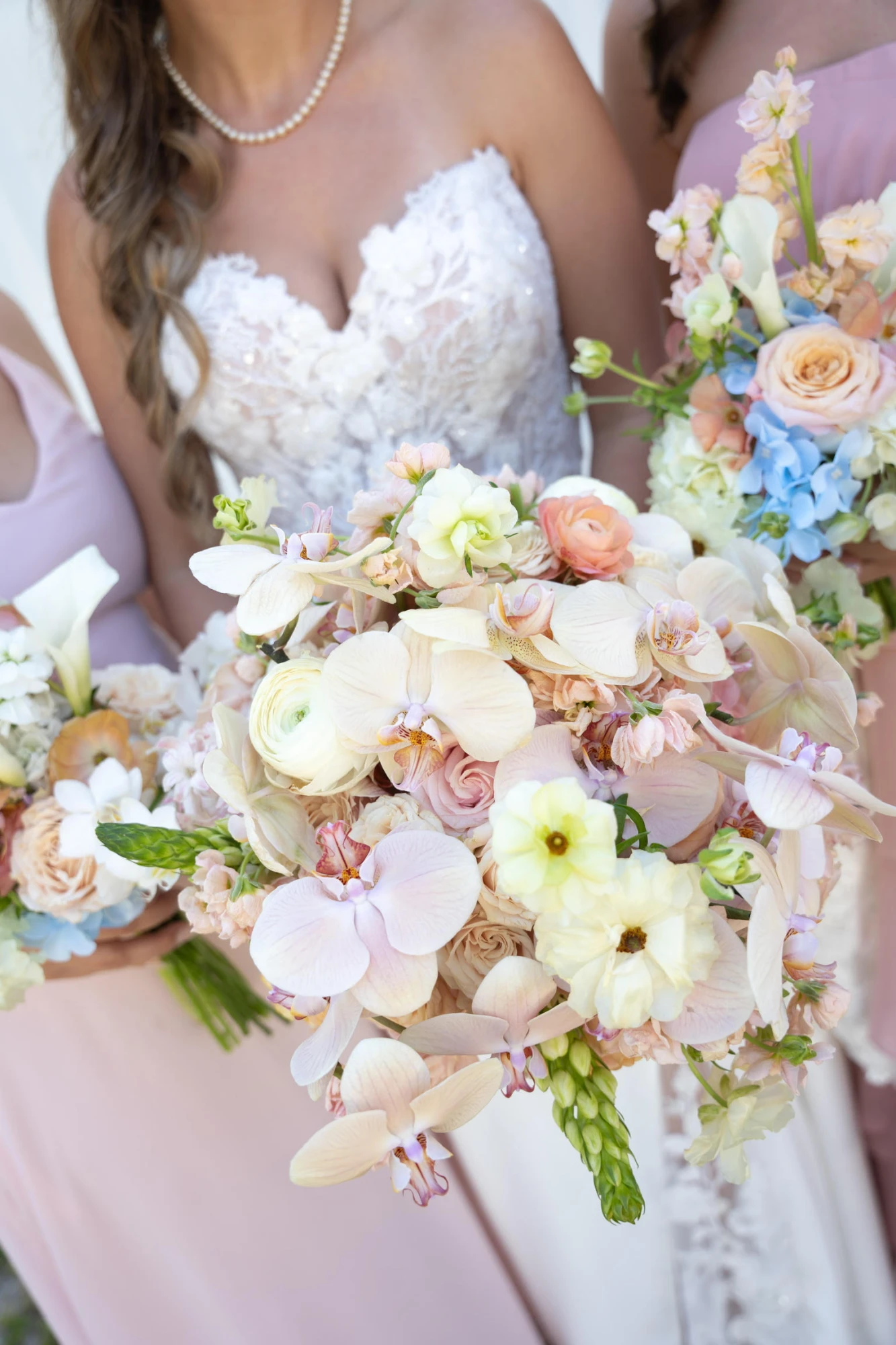 A lush, hand-designed pastel bridal bouquet of orchids, ranunculus and garden roses
