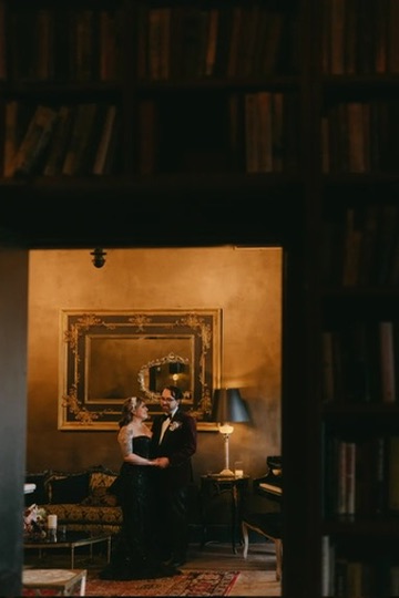 A couple share a quiet candlelit moment framed by a gilded mirror at a luxury wedding