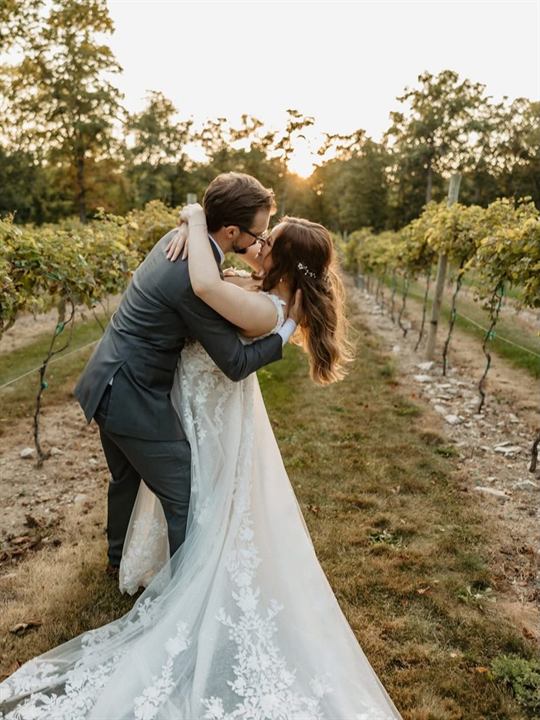 Bride and groom kissing in a sunlit vineyard at golden hour