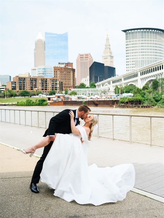 A couple by the water with a city skyline behind them