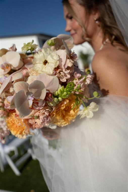 A bride holding a warm-toned bouquet of garden roses and orchids