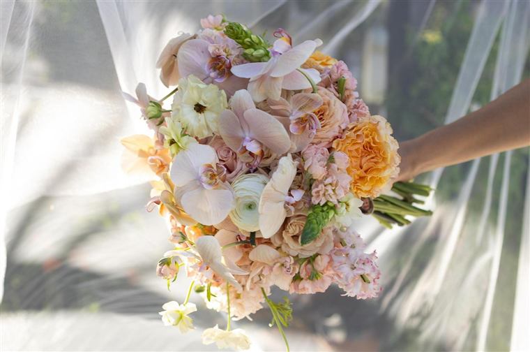 A lush hand-designed bouquet of garden roses and orchids in blush and peach