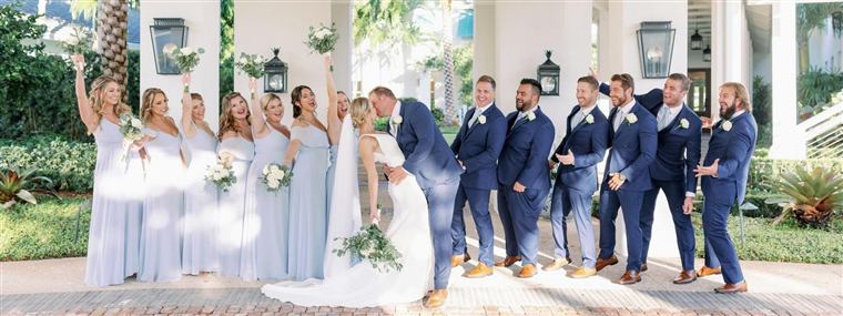 A wedding party of bridesmaids in dusty blue and groomsmen in navy suits